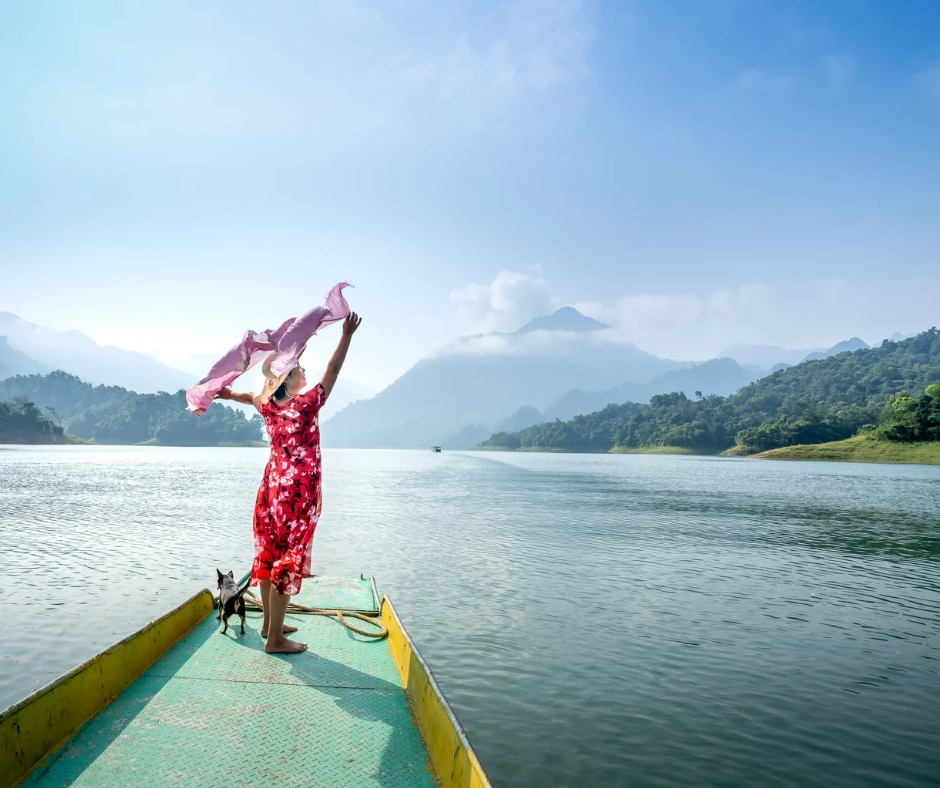Eine Frau steht auf einem Steg am See und hält ein Tuch in den Händen. Sie trägt einen Hut und strahlt Freiheit und Entspannung aus. Das Bild vermittelt das Gefühl von Erholung und Urlaub in der Natur.