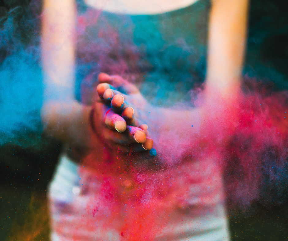 Hände klatschen zusammen, erzeugen eine Farbenexplosion auf schwarzem Hintergrund